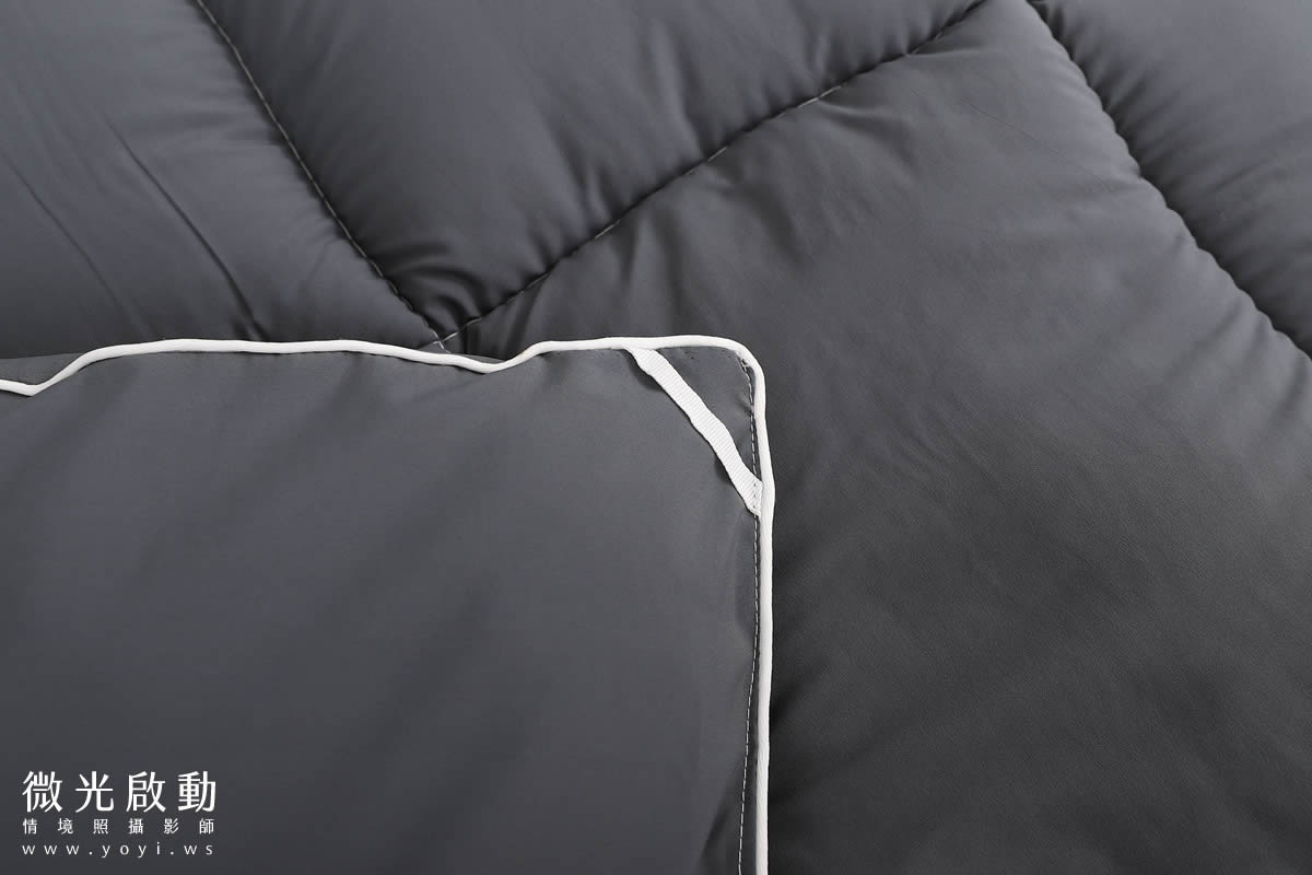 專業商品攝影。一張淺綠色棉被，平整地鋪開，展現其輕盈和簡潔的設計。標示寢具攝影、攝影服務。