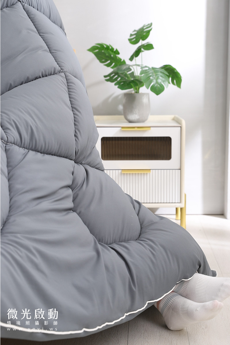 居家商品攝影。深灰色寢具在淺色臥室內，搭配白色床頭板，營造出高雅的視覺效果。適用於寢具攝影、攝影專案。