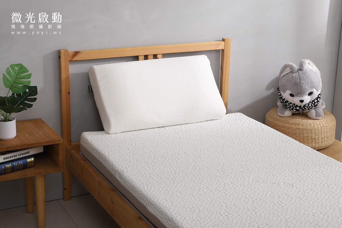 攝影服務。淺灰色棉被在木質地板上，其自然垂墜的線條與光影變化，展現其柔軟性。標示寢具攝影、商品攝影。