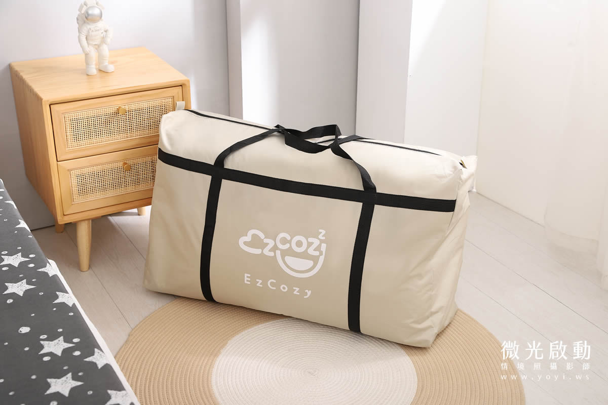 居家商品攝影。一張淺灰色棉被，其邊緣的精緻滾邊設計在特寫鏡頭下清晰可見。標示寢具攝影、商品攝影。