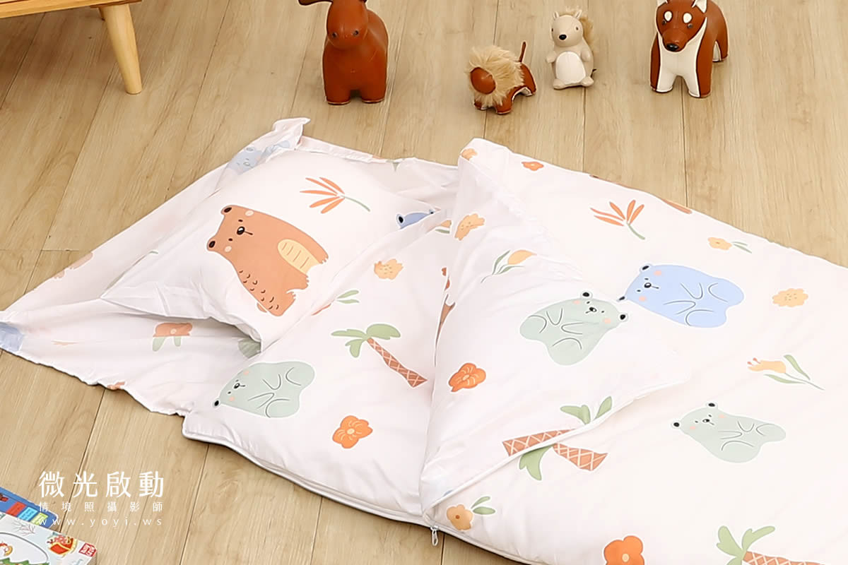 兒童商品攝影：特寫新生兒小手，輕撫在白色雲朵造型寢具上，呈現產品柔軟親膚的細節。