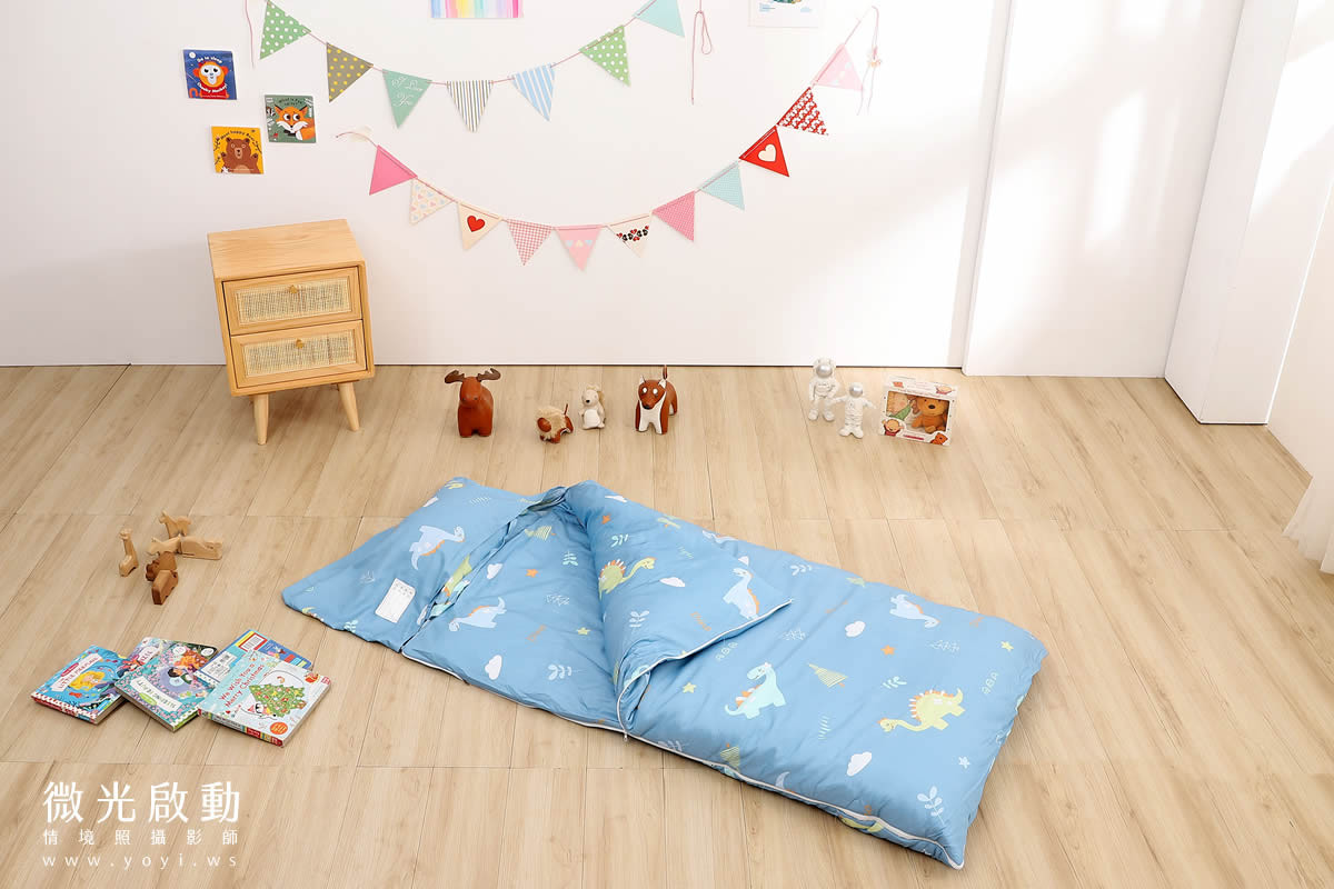 寢具攝影：寶寶安詳地睡在白色雲朵床墊上，淺灰色棉被輕輕覆蓋，展現產品的舒適與安心感。