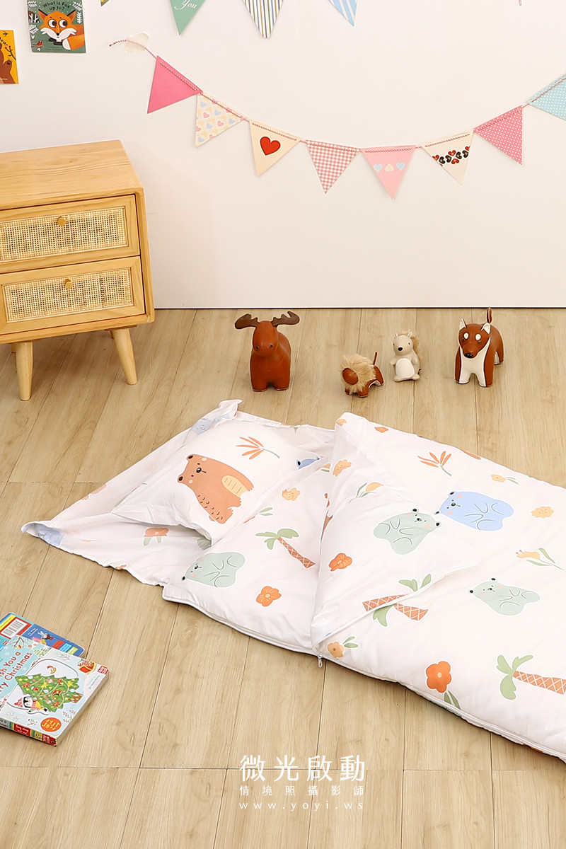 寢具攝影：俯視角度拍攝寶寶腿部與蓋在身上的棉被，展示全套寢具的搭配與使用情境。