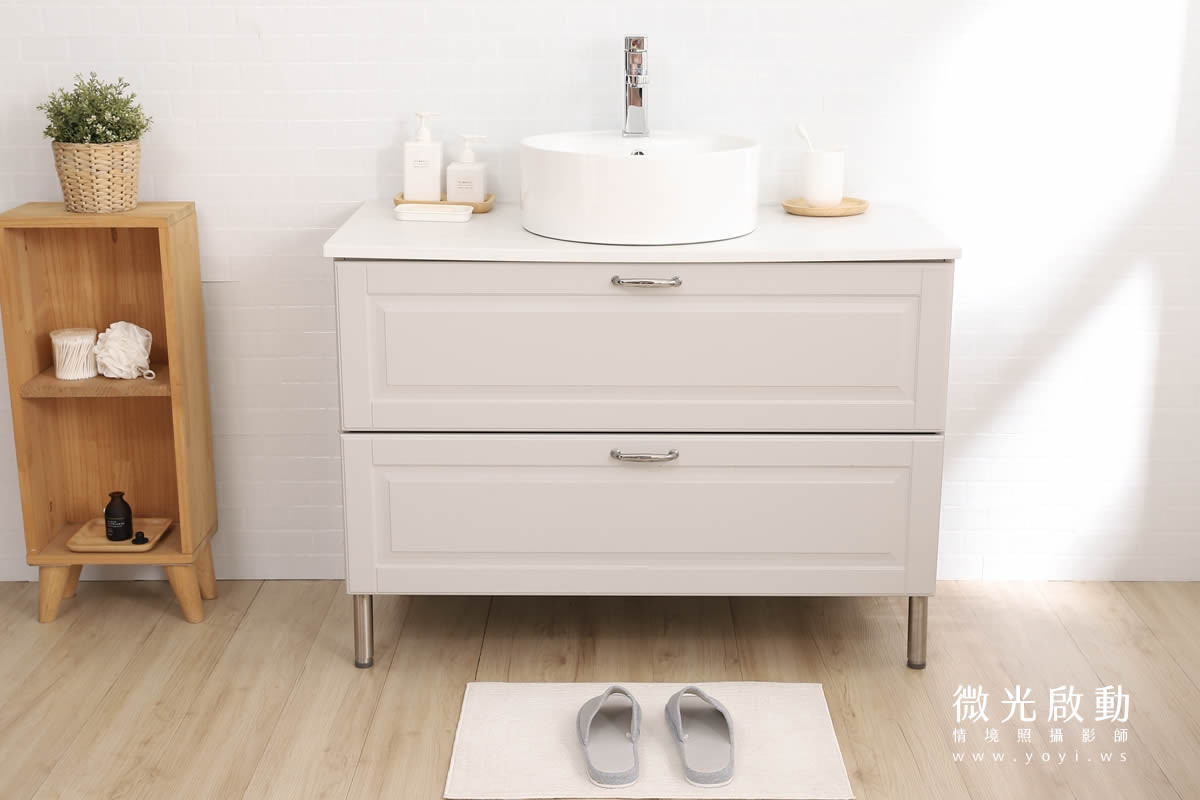 特寫：攝影棚浴室場景洗手台與浴櫃近景，淺米色雙抽屜櫃體，搭配白色圓形面盆，適合衛浴設備特寫
