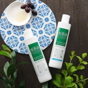 PUTAMARTA柔順洗髮精（Soft Shampoo）兩瓶，以頂級靜物攝影風格呈現。白色瓶身搭配新鮮薄荷葉和橄欖枝，置於深色木紋背景上。道具包含藍白圖案的異國風托盤，強調天然草本與 SPA 質感。