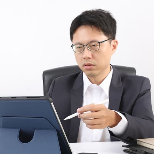 專業包套服務：穿西裝的專業人士使用平板電腦工作，象徵高效整合的拍攝、修圖與影片製作服務。